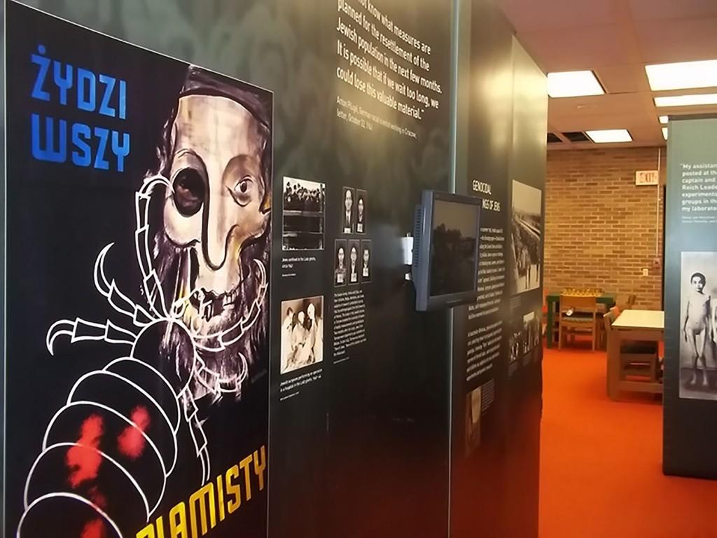 The traveling holocaust exhibit in Nash Library is a walk-through display that features mixed media like this wall with pictured artifacts and video clips.