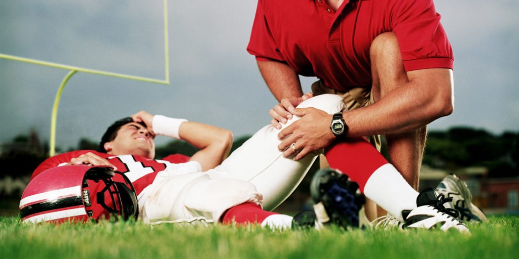 Football team doctor with injured player on field