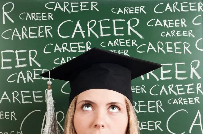 Girl in graduation cap looking up at the word "career" written behind her on a chalkboard. (Photo/University of Connecticut)