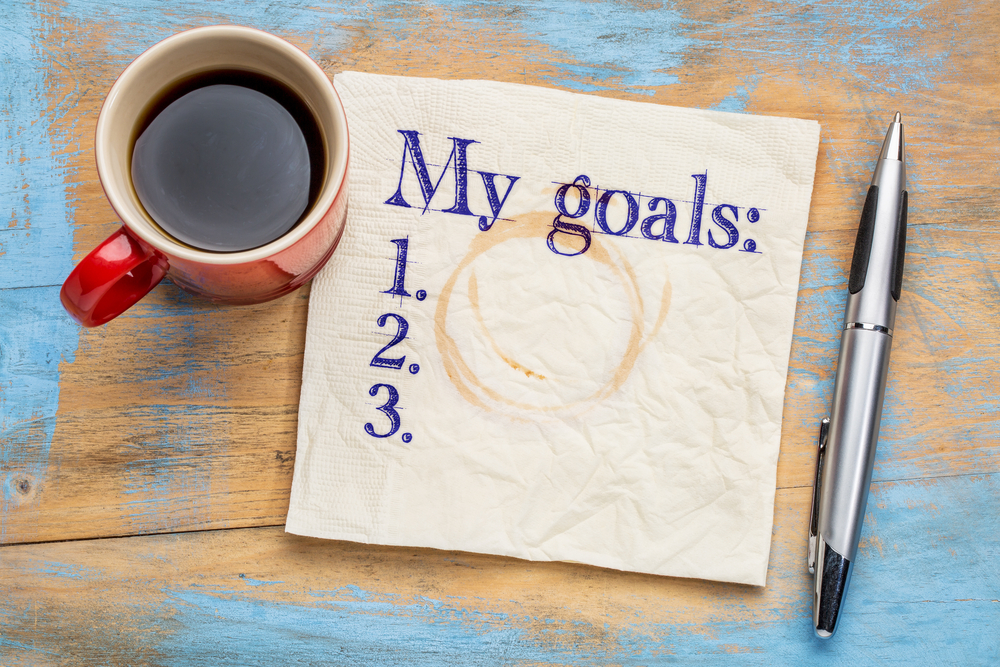 Image depicts paper with ‘My goals’ written, a cup of coffee, and a pen. (Photo/monarchmoney.com)